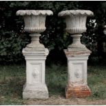 PAIR OF RECONSTITUTED STONE URNS, neo-classical flared form with stiff leaf and fluted decoration,