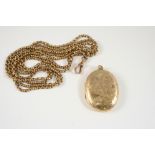 A 9CT. GOLD OVAL SHAPED LOCKET PENDANT with foliate engraved decoration to the front case, 4.5 x 3.
