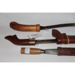 THREE 20thC DYAK KNIVES. A Dyak knife with short Parang shape blade of 6" , with wooden hilt and