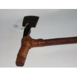 A 20thC DYAK AXE. Mounted on a springy 27" shaft with 5.3/4" enlarged grip, the axehead with Yusup