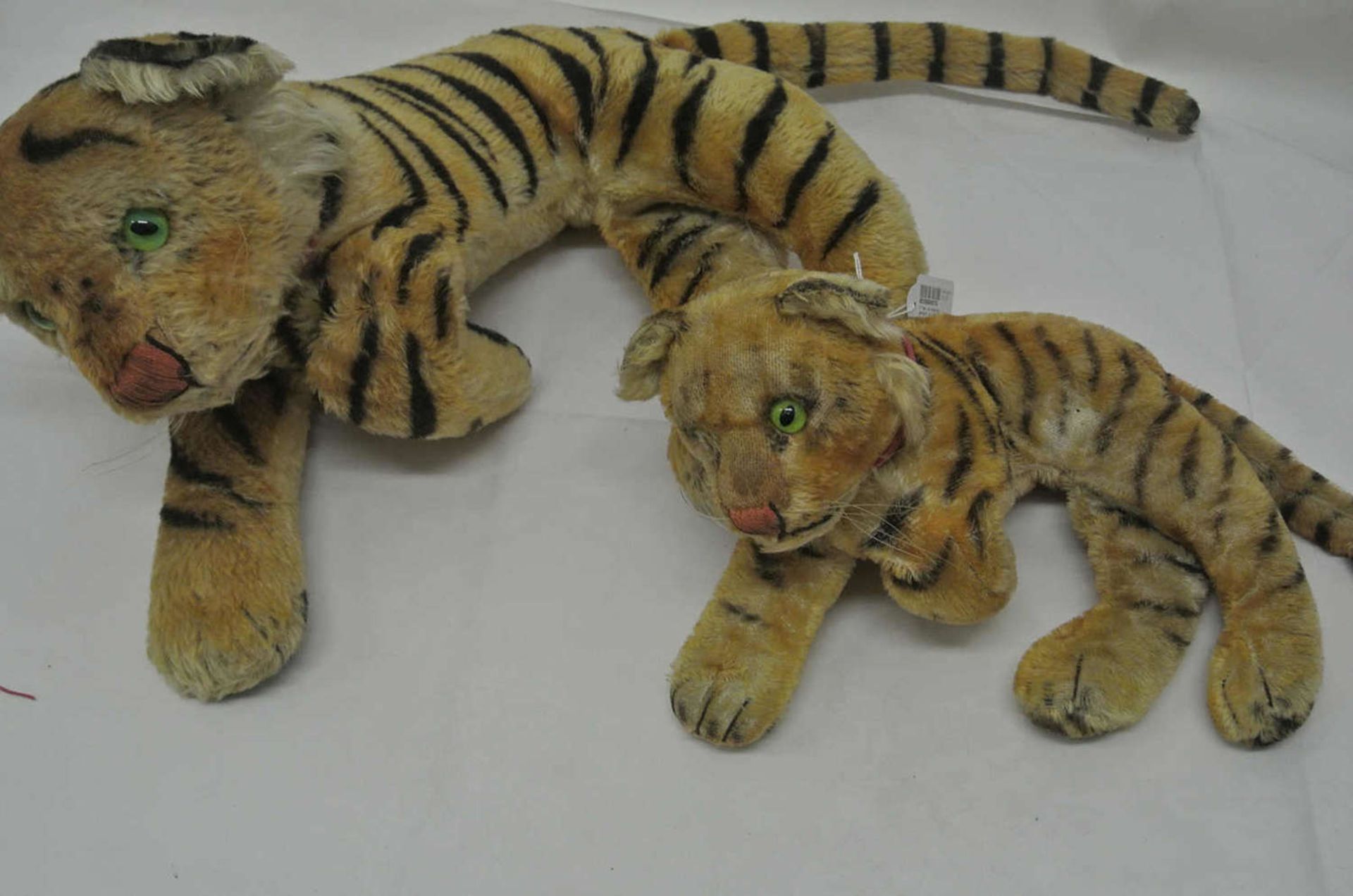 2 Tiger, mit Holzwolle gestopft, um 1930. Mit Glasaugen. Beim kleinen Tiger fehlt 1 Auge. Maße des