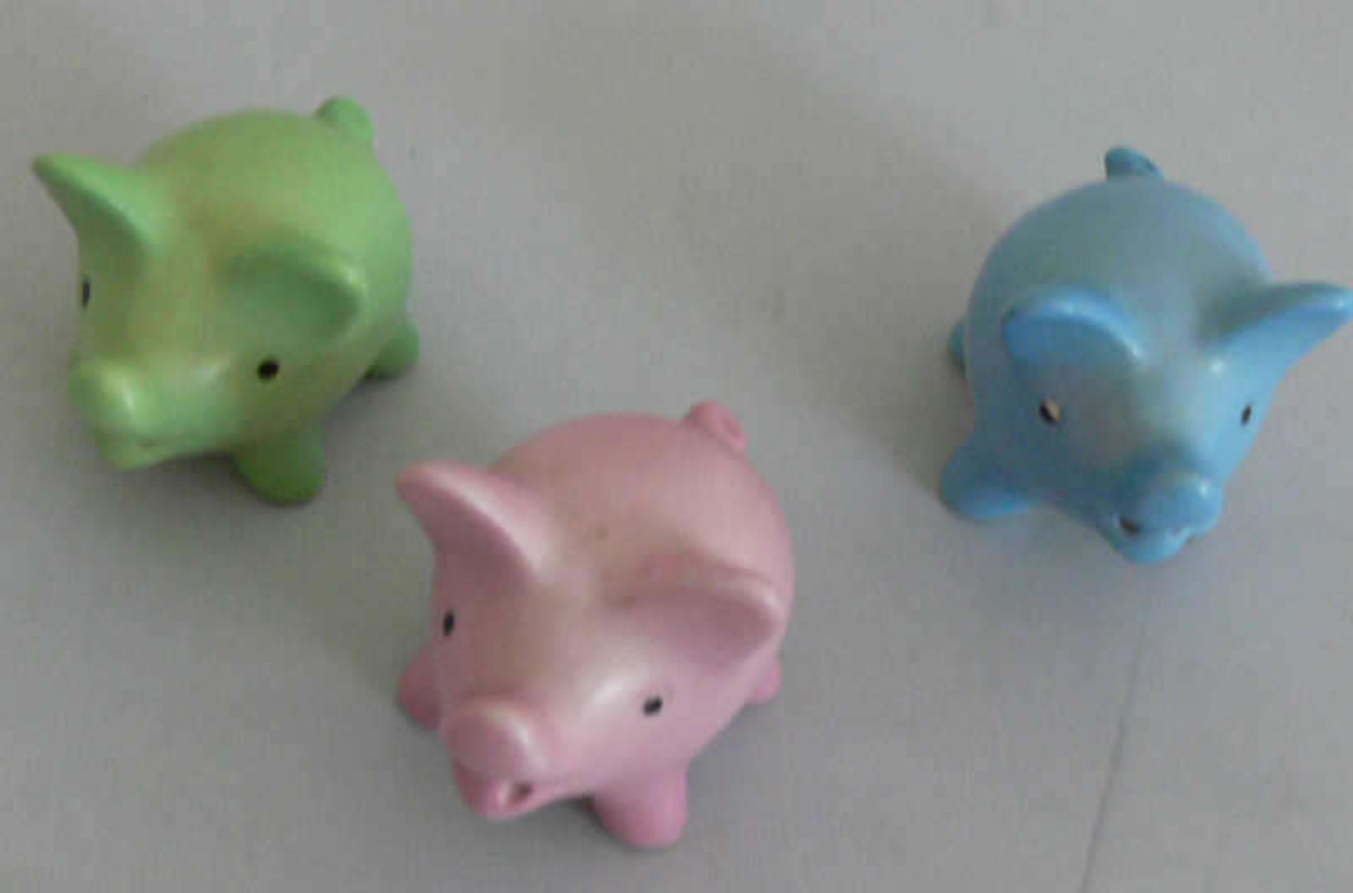 3 kleine Hummel - Schweinchen in grün / rosa und blau. Das rosa Schweinchen hat am hinteren Bein