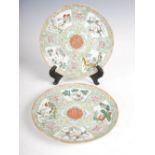 A pair of Chinese porcelain famille rose green ground plates, Qing Dynasty, decorated with central
