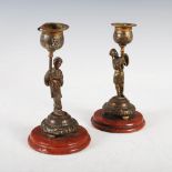 A pair of late 19th century bronze Chinoiserie candlesticks, formed with mandarin figures holding