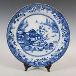 A Chinese porcelain blue and white dish, Qing Dynasty, decorated with pavilions, figures and sampans