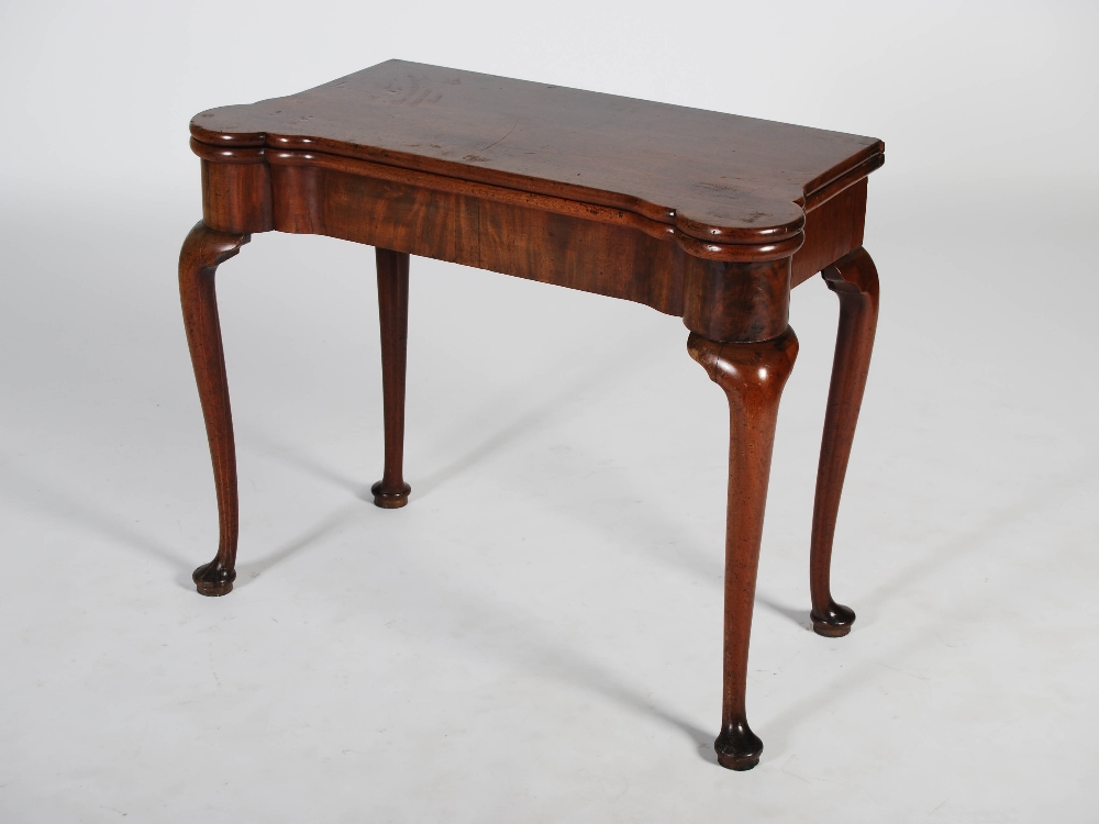 A George III mahogany concertina action card table, the shaped rectangular top opening to a green