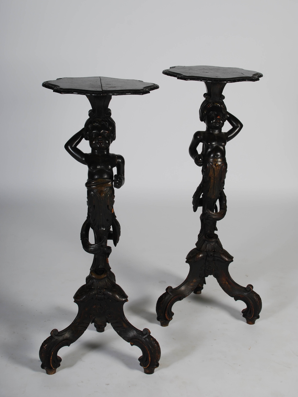 A pair of late 19th/early 20th century carved and stained wood blackamoor torcheres, the shaped