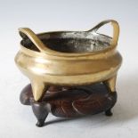 A Chinese gilt bronze censer, Qing Dynasty, the rim with two raised handles, raised on three pronged