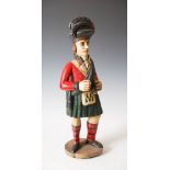 A 19th century carved and painted wood tobacco advertising figure in the form of a Highlander taking