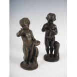 A pair of late 19th century bronze putti, one modelled standing holding a bird, the other holding
