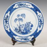 A Chinese porcelain blue and white plate, decorated with peony, lotus and tree within a diaper