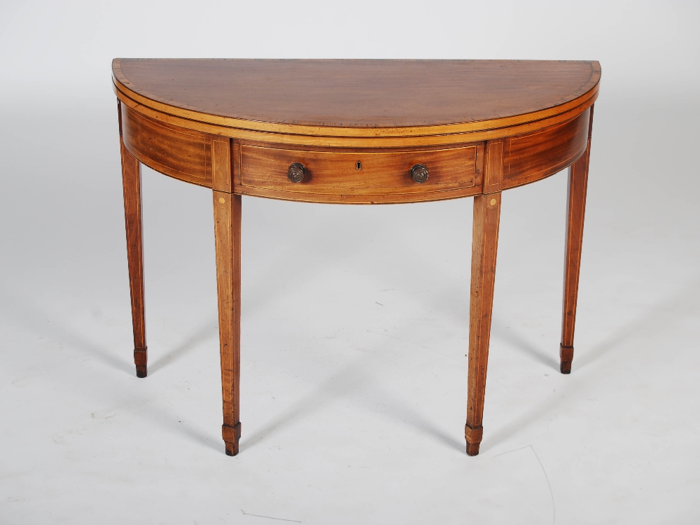 A George III mahogany and satinwood banded demi lune card table, the hinged top opening to a puce