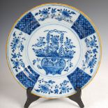 A 19th century Delft pottery charger, decorated with a basket issuing flowers within a panelled