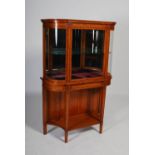 A fine Edwardian satinwood and ebony inlaid display cabinet on stand, the upper section with a