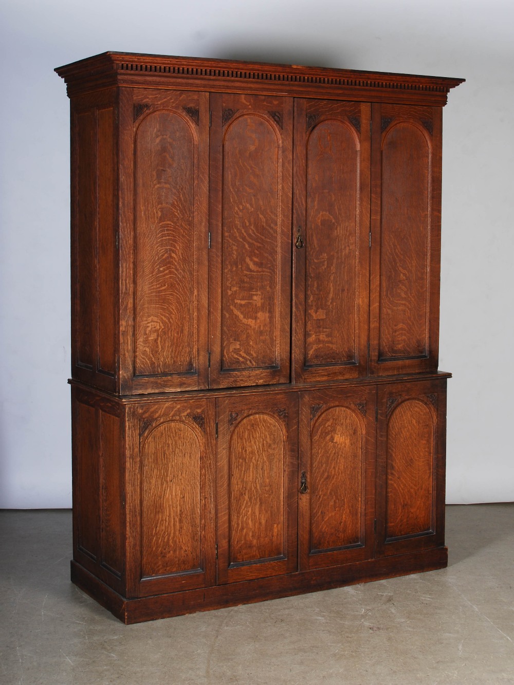 A Victorian oak cupboard, the moulded cornice and dentil frieze above a pair of double hinged,