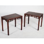 A pair of Chinese dark wood occasional tables, the rectangular panelled tops above a pierced