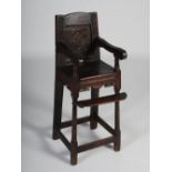 A 19th century oak child's high chair, the panelled back carved with lozenge and foliate detail,