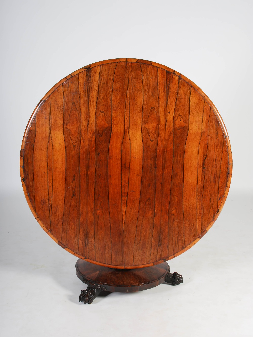 A 19th century rosewood snap top dining table, the hinged circular top raised on a tapered octagonal