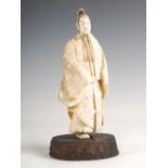 A Japanese ivory okimono of a scholar, Meiji period, modelled standing wearing long robes, on a