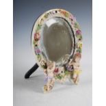 A Dresden porcelain floral encrusted dressing table mirror, the oval bevelled mirror plate within