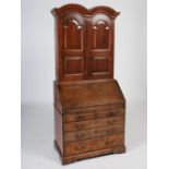 A George III oak bureau bookcase, the double domed moulded cornice above a pair of panelled cupboard