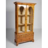 An antique and later walnut display cabinet, the rectangular top and concave frieze above a pair