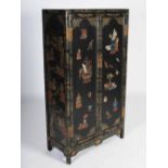 A Chinese lacquered cupboard, the pair of rectangular panelled cupboard doors decorated with