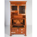 An oak Arts & Crafts style bureau bookcase, the moulded cornice above a plain frieze centred with