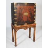 An early 20th century chinoiserie decorated lacquered cabinet on stand, the cabinet with a pair of