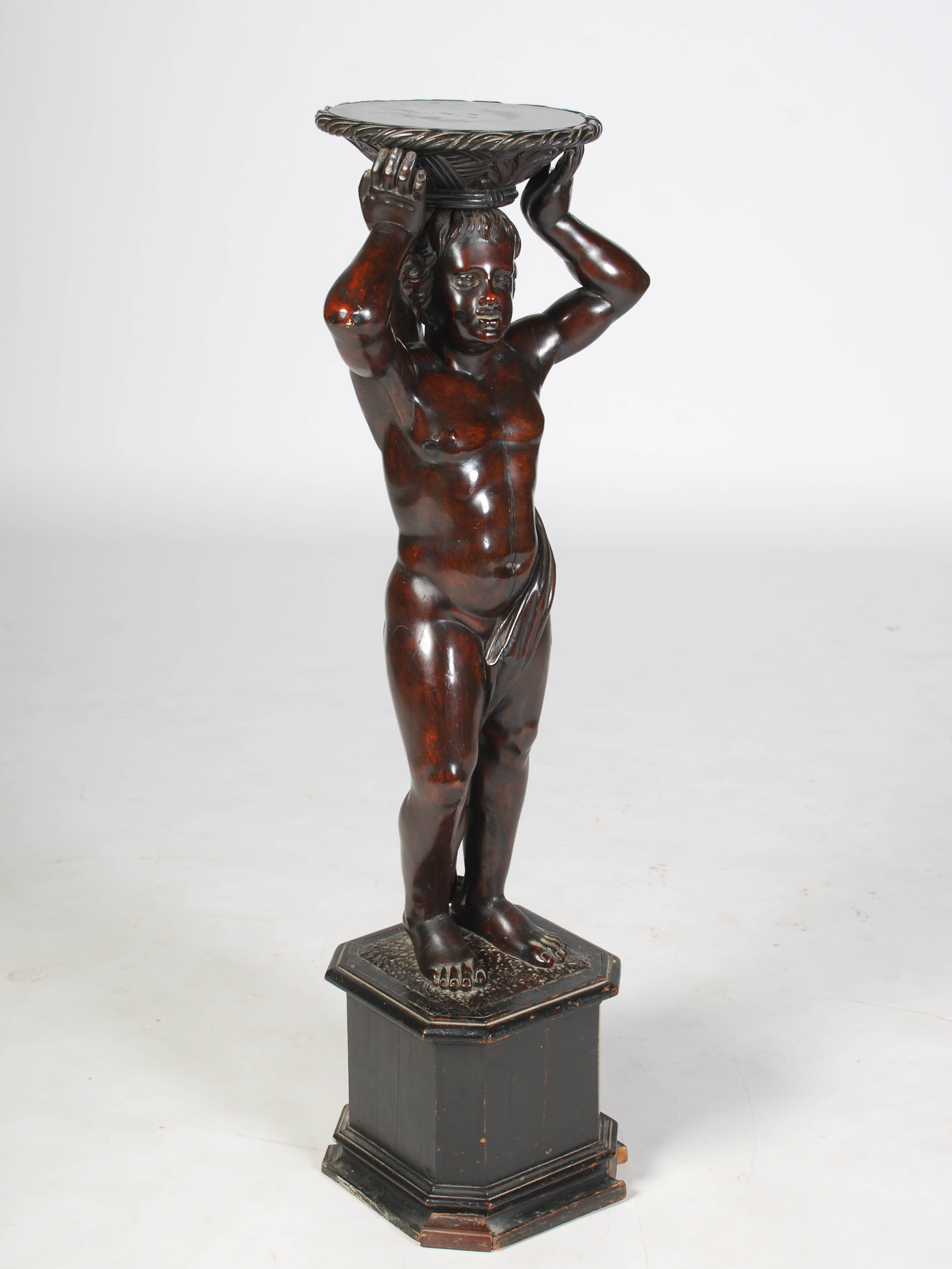 A late 19th century carved and stained wood figural torchere, carved with a semi clad male figure