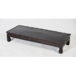 A Chinese dark wood low table, Qing Dynasty, the rectangular panelled top raised on four short