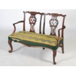 A George III mahogany double chair back settle, the foliate carved top rails above pierced and