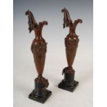 A pair of early 20th century bronzed spelter ewers, cast with a frieze of putti, with scroll over