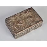 A Japanese silver box and cover, Meiji Period, the hinged cover and sides decorated in relief with