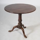 A George III mahogany snap top tripod table, the hinged circular top resting on a bird cage and