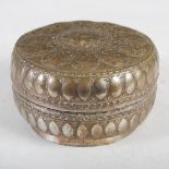A late 19th century Indian white metal circular box and cover, decorated with embossed panels of