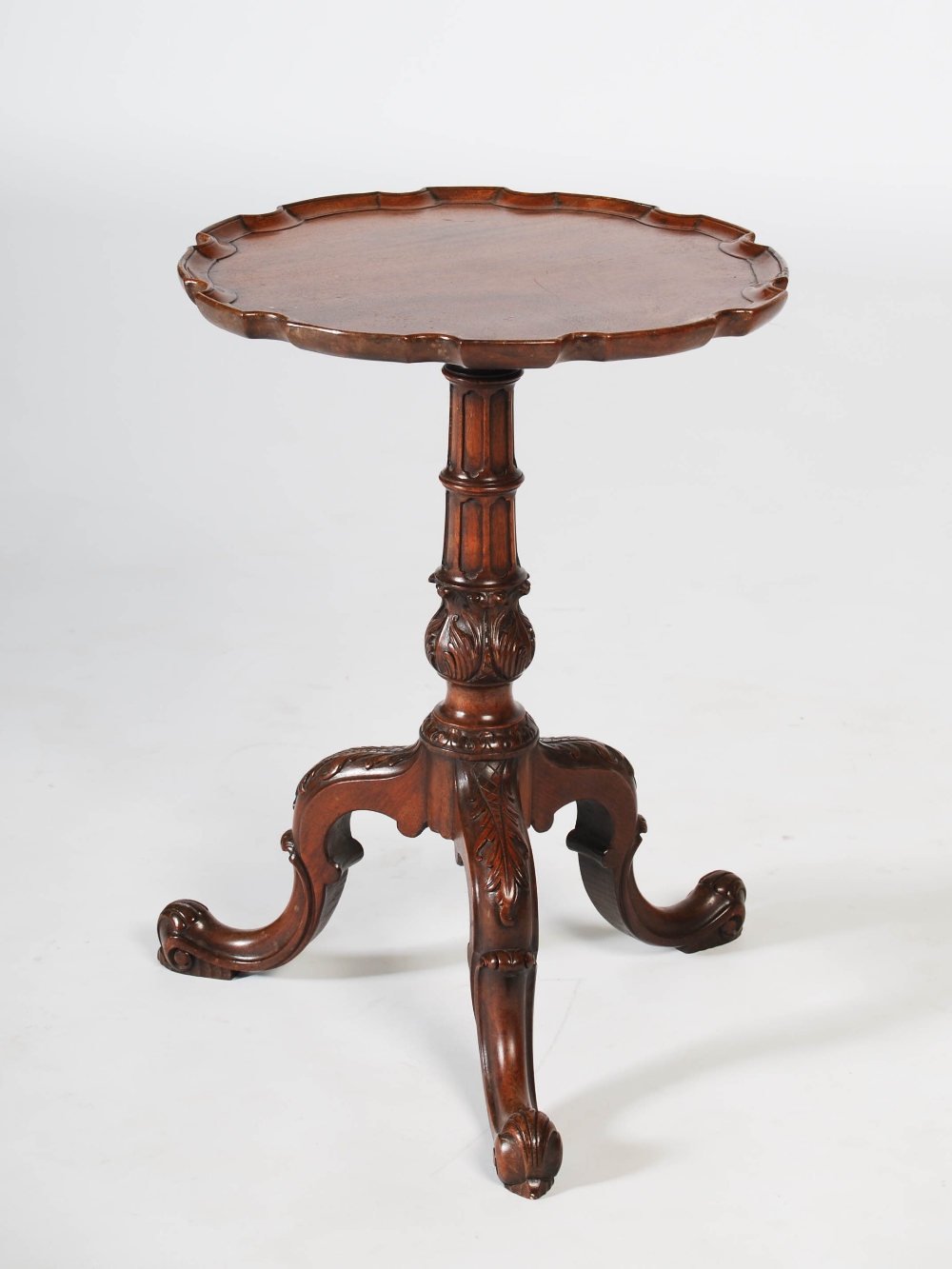 A George III style mahogany tripod occasional table, the circular top with pie crust edge, raised on