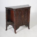 A Chinese dark wood side cabinet, the shaped panel top above a pair of panelled cupboard doors