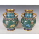 A pair of Chinese green ground cloisonne twin handled vases, Qing Dynasty, decorated with lotus