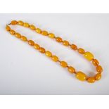 A SIMULATED butterscotch amber necklace, comprising twenty eight beads, gross weight 46.3 grams