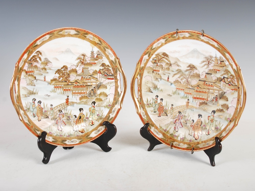 A pair of Japanese Kutani twin handled cabinet plates, decorated with figures and pavilions in a