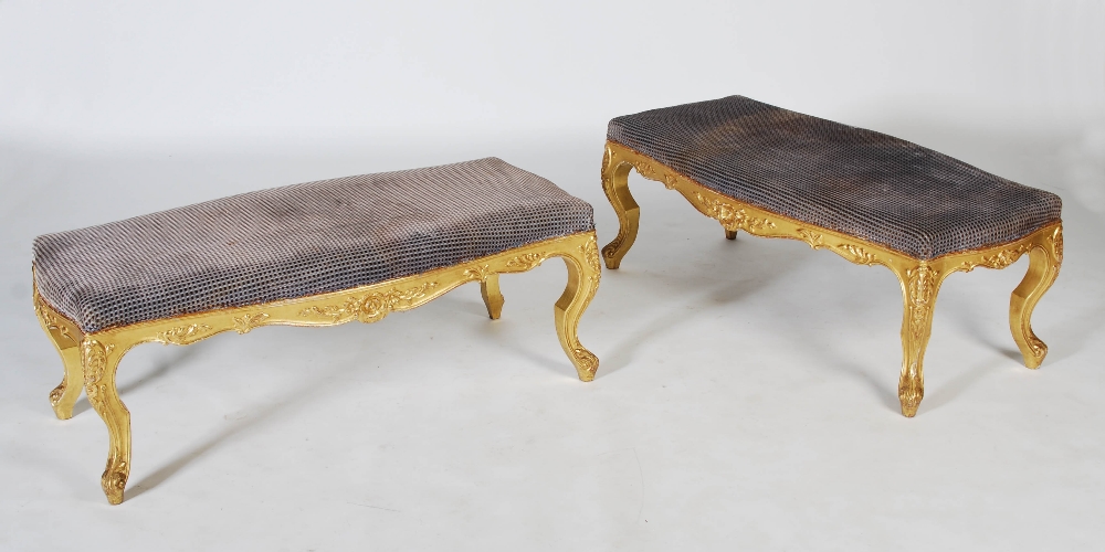 A pair of Victorian style gilt wood stools, the rectangular upholstered tops with a serpentine edge,