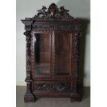 A late 19th century stained oak display cabinet, with acanthus carved and dentil cornice above a