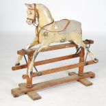 A late 19th/early 20th century painted pine rocking horse, with inlaid glass eyes, leather bridle