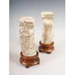 A pair of Japanese ivory tusk vases, Meiji Period, carved in relief with figures, pine trees and