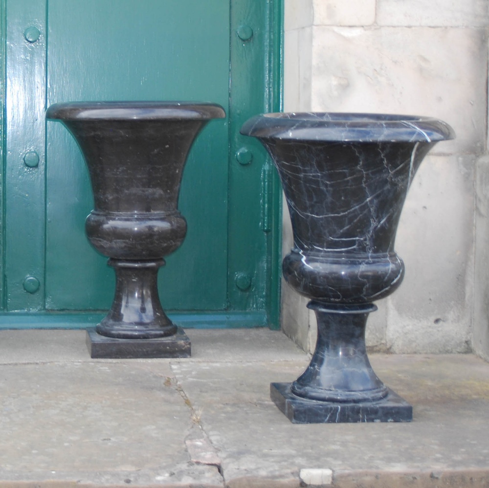 A pair of 20th century black and white veined marble urns, formed in two sections, resting on square