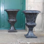 A pair of 20th century black and white veined marble urns, formed in two sections, resting on square