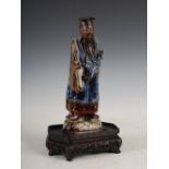 A Chinese porcelain figure of a sage, covered in a sang-de-boeuf, blue and green glaze, on an