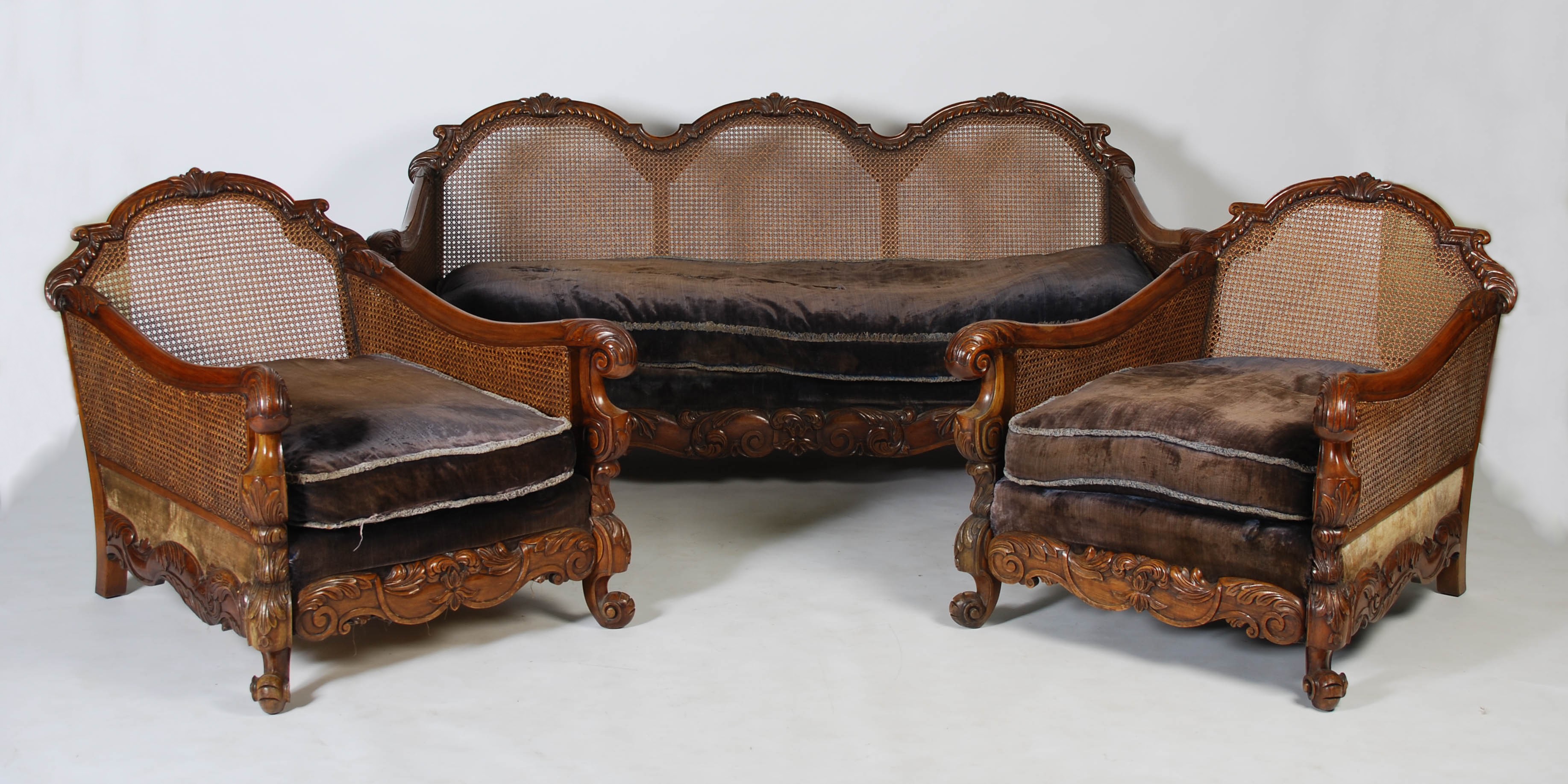 An Edwardian walnut three piece Bergere suite, comprising; three seat sofa and two armchairs, with
