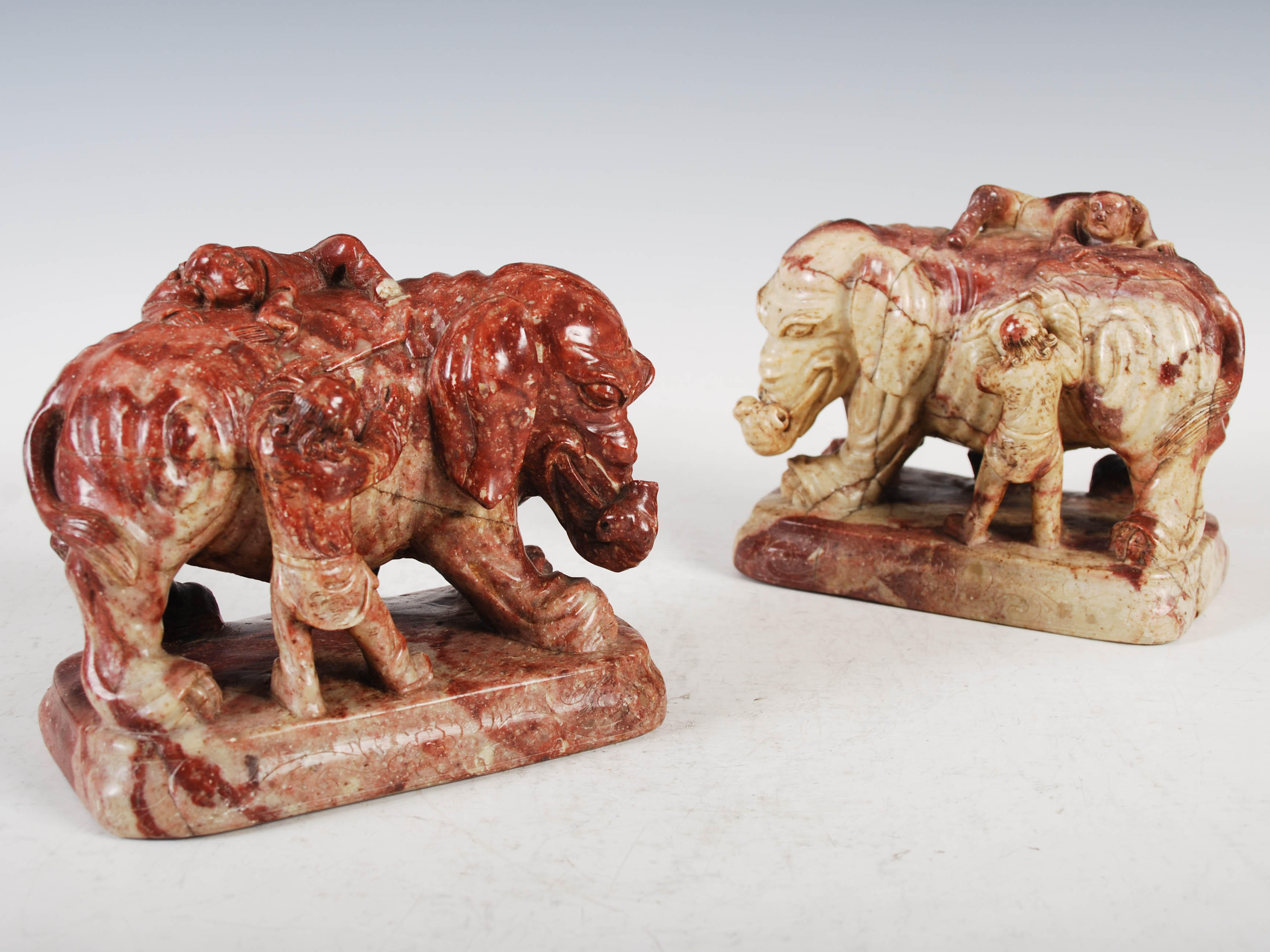 A pair of Chinese soapstone elephants, late Qing Dynasty, carved standing with pairs of attendant
